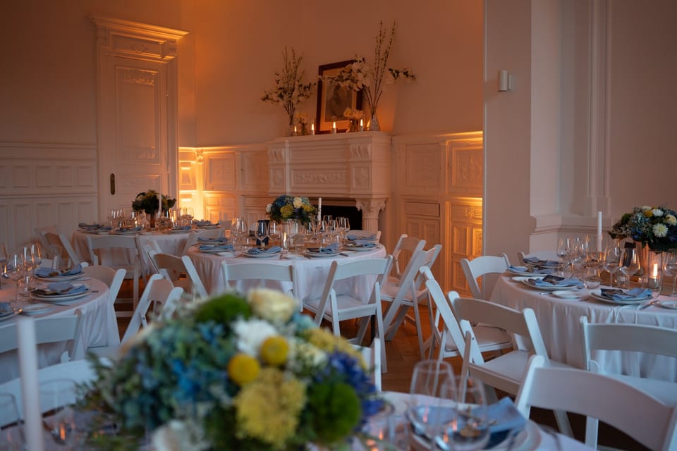Dîner d'anniversaire dans le salon du 119 : tables rondes, bouquets bleus et jaunes devant la cheminée, lumière ambrée