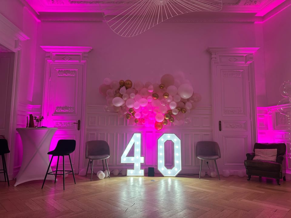 Salon du 119 illuminé de rose pour un anniversaire de 40 ans : chiffres lumineux, arche de ballons et boiseries