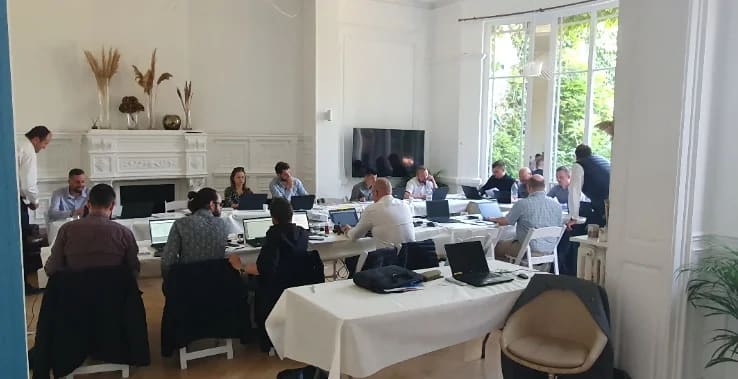 Collègues réunis autour de tables dans le salon lumineux du 119 lors d'un séminaire d'équipe