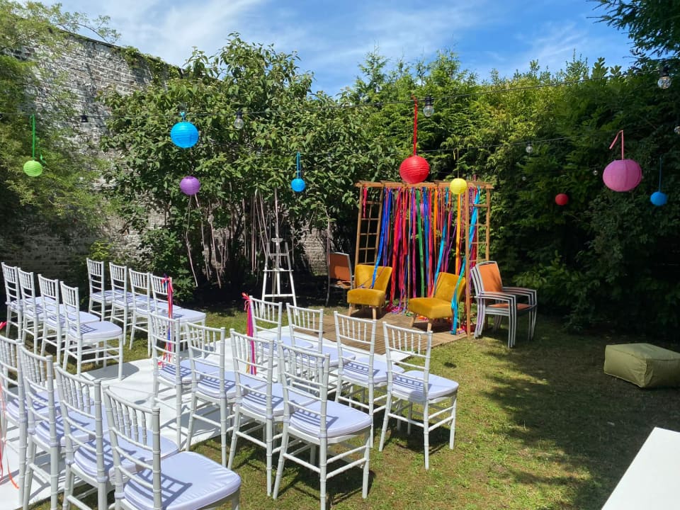 Chaises blanches et arche de rubans colorés dans le jardin pour un mariage