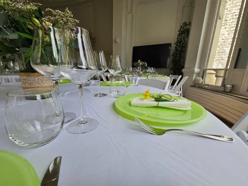 Table dressée pour une fête de famille, assiettes vertes et verres à pied