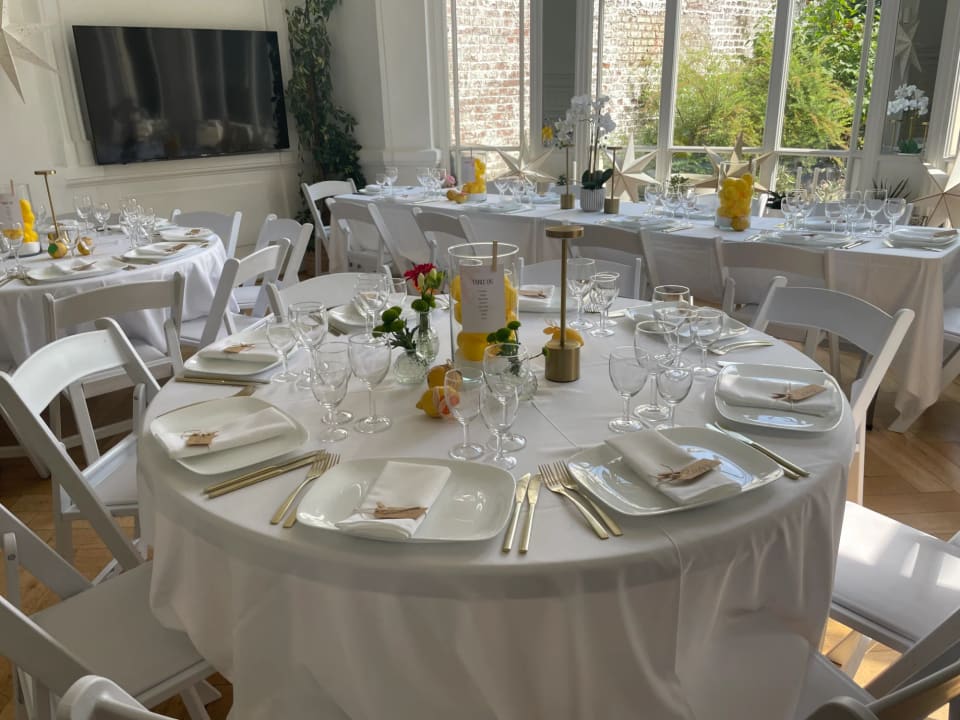 Salle de réception dressée pour un déjeuner de famille, baies vitrées sur le jardin