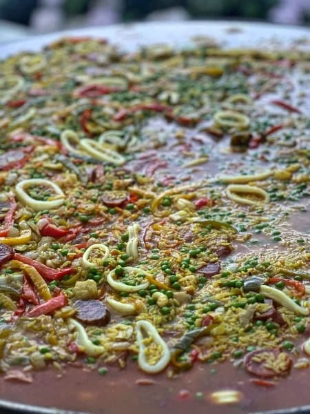 Paëlla en cuisson : calamars, poivrons et petits pois
