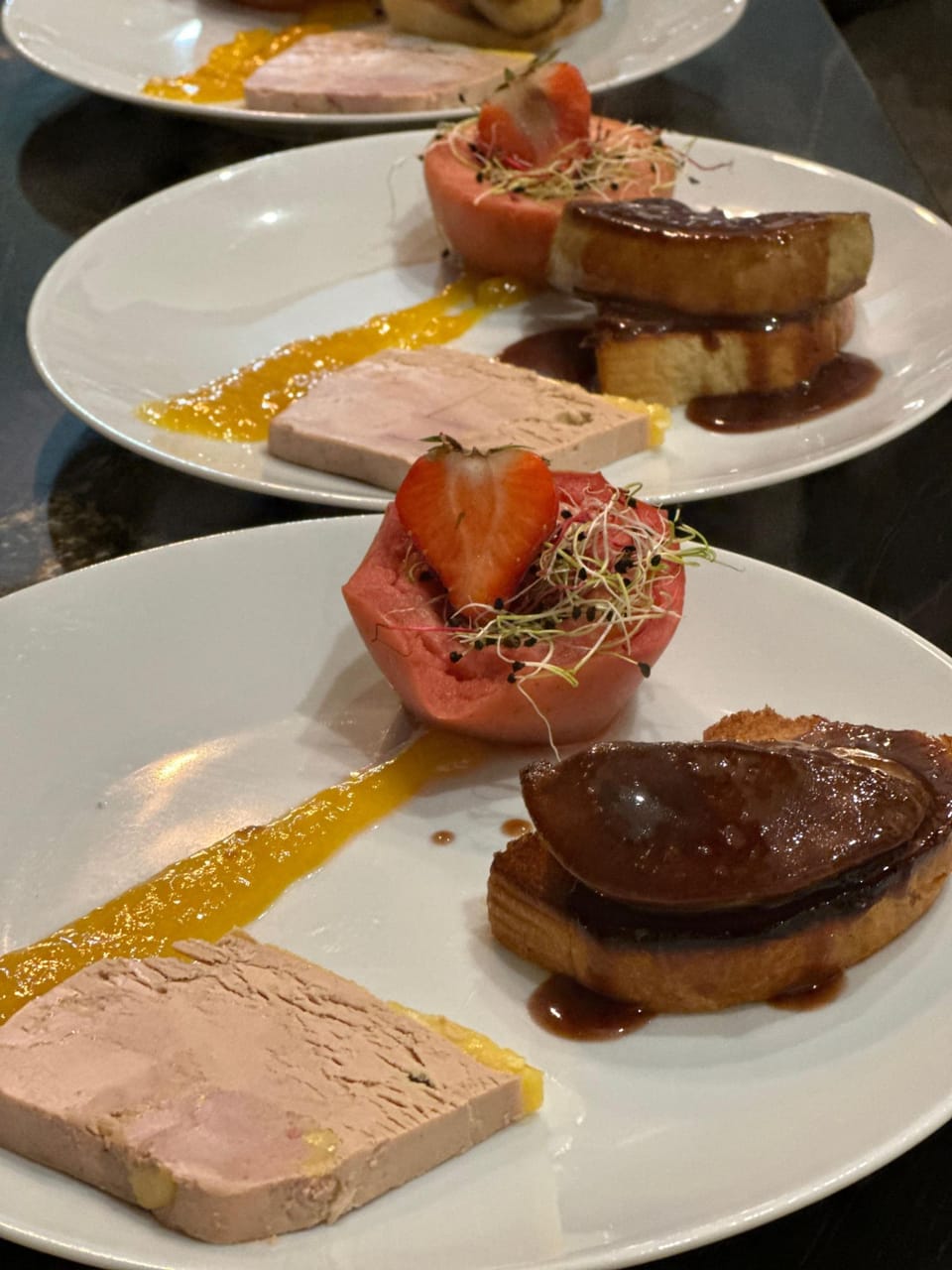 Entrée du chef : terrine de foie gras, foie gras poêlé sur pain toasté et fraise, dressés sur des assiettes alignées