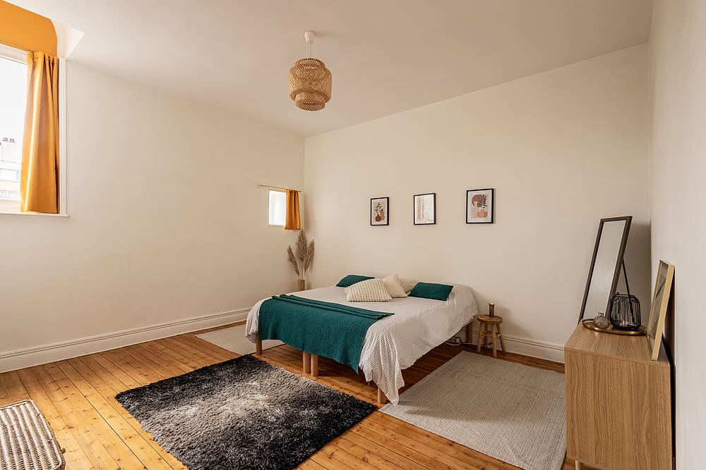 Chambre avec lit, plaid vert et parquet ancien, appartement #3 du 119