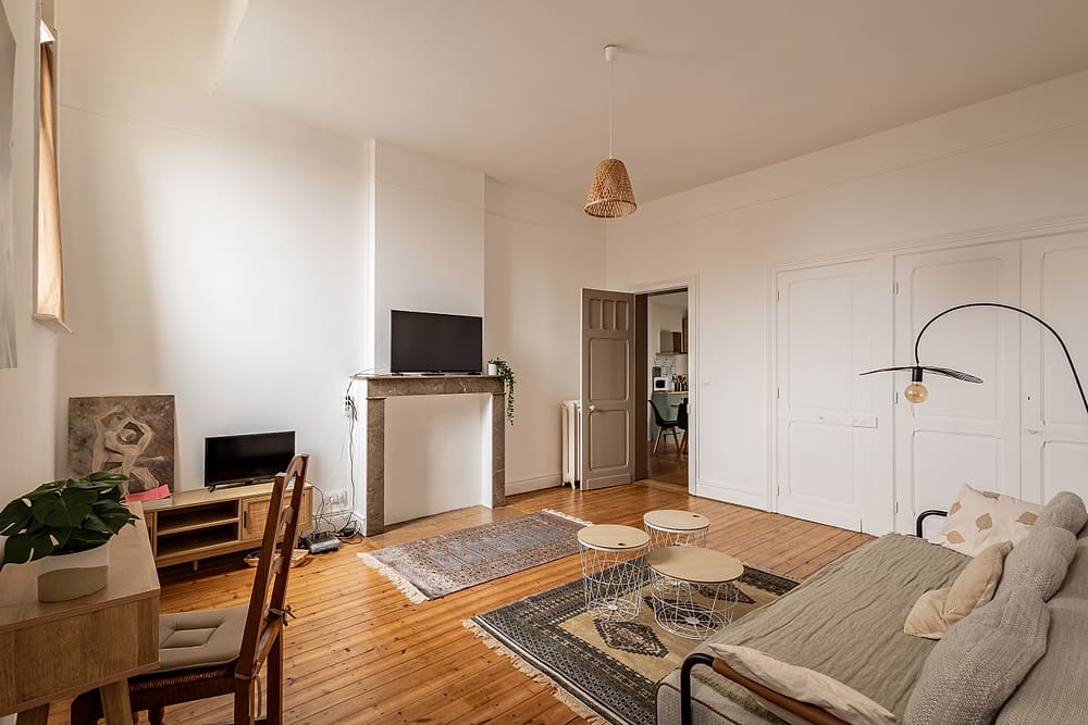 Salon lumineux avec canapé, tapis et parquet ancien, appartement #3 du 119