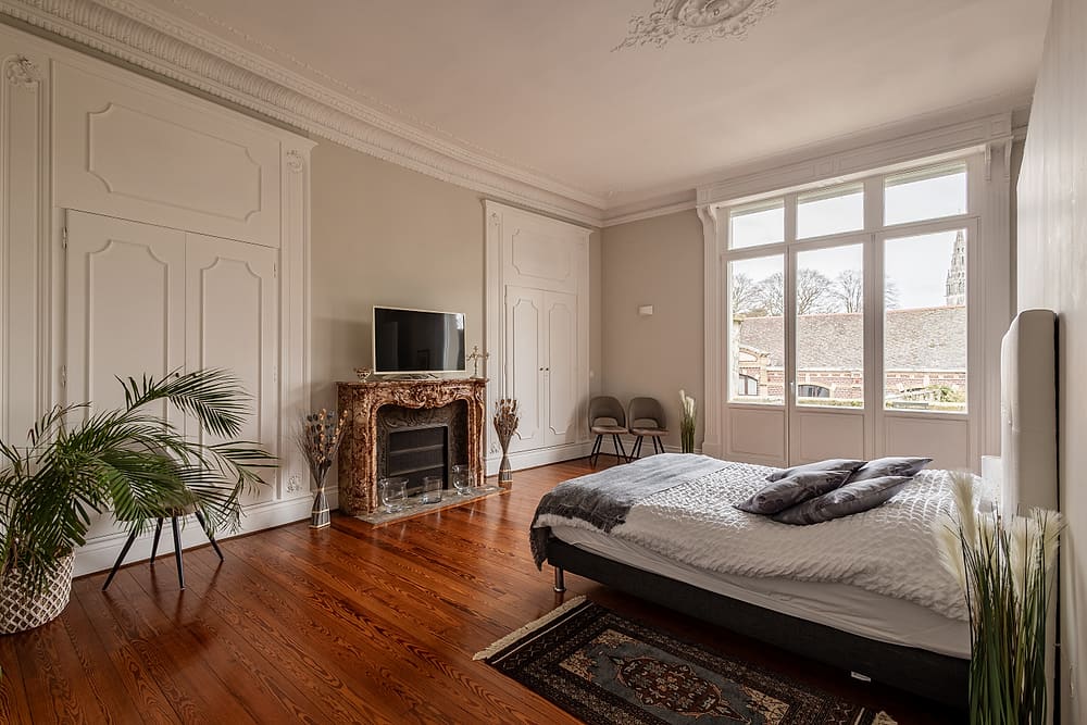 Chambre principale de l'appartement Prestige #1 du 119 à Valenciennes : lit double 160 cm, cheminée en marbre et parquet ancien