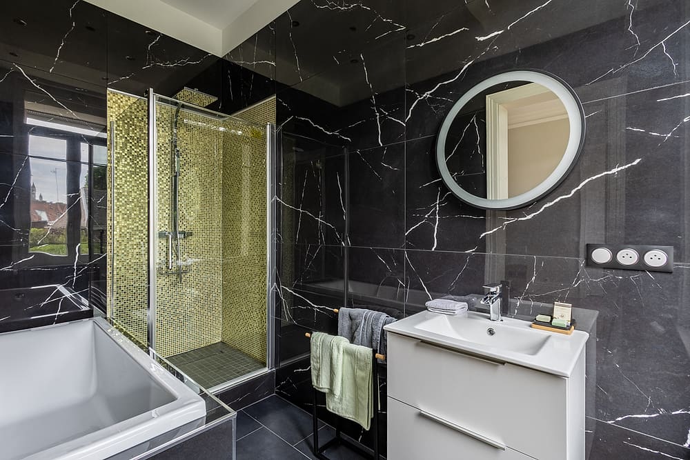 Salle de bain de la chambre des glaces avec baignoire, vasque et miroir rond lumineux