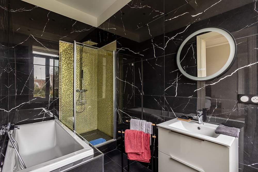 Salle de bain attenante à la chambre des glaces : douche en marbre noir et mosaïque dorée