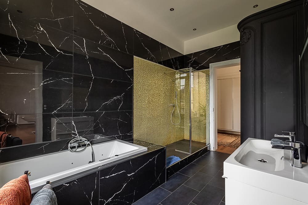 Salle de bain attenante à la chambre principale : baignoire balnéo et douche en marbre noir