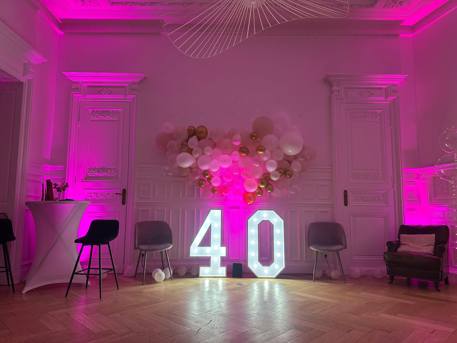 Salon du 119 en lumière rose pour un anniversaire : arche de ballons et chiffres lumineux