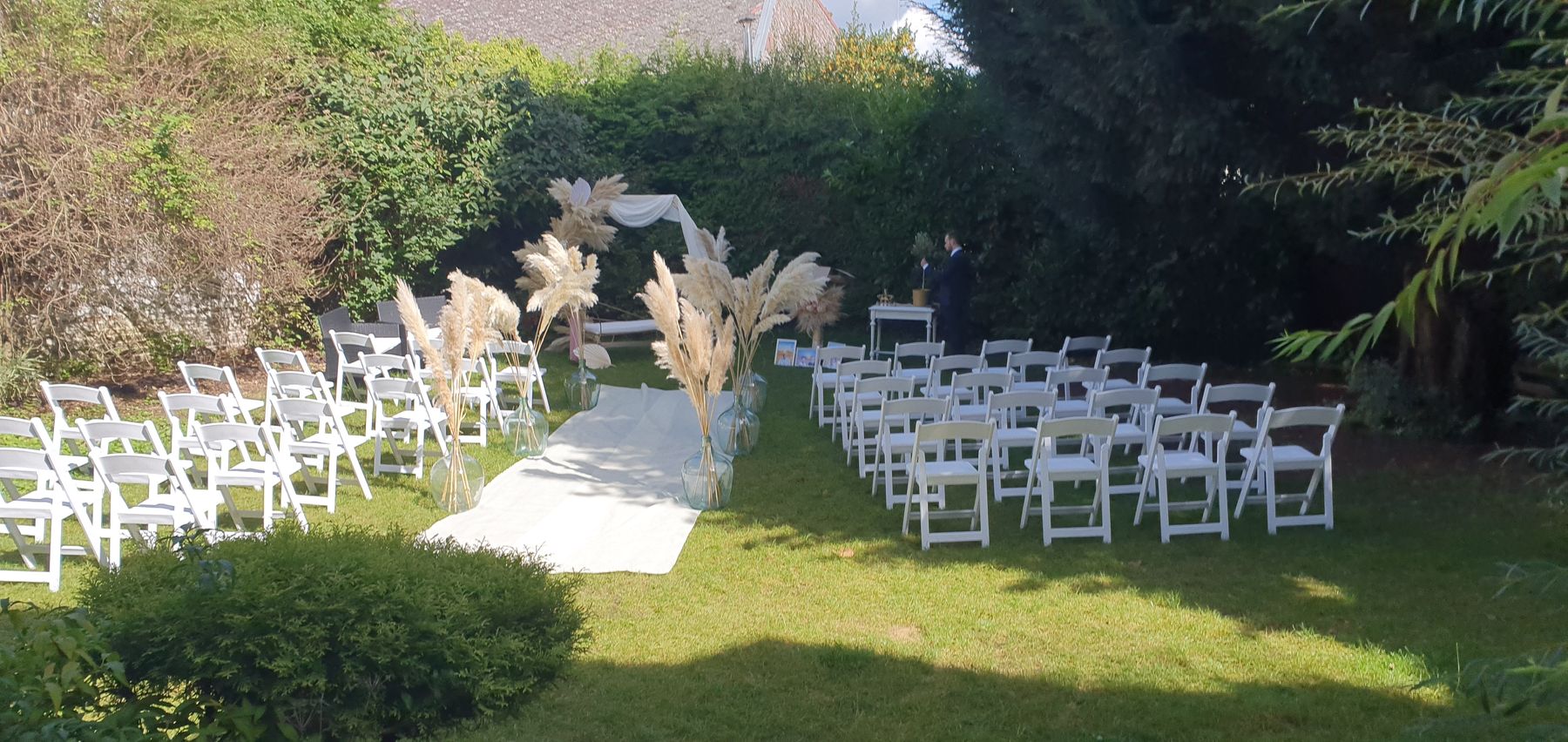 Cérémonie laïque préparée dans le jardin du 119 : chaises blanches, allée et arche d'herbes de la pampa
