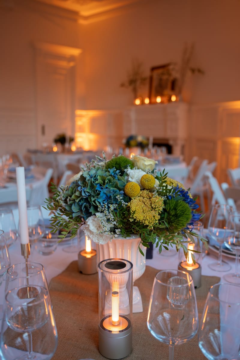 Bouquet d'hortensias bleus et de craspedias jaunes sur une table dressée