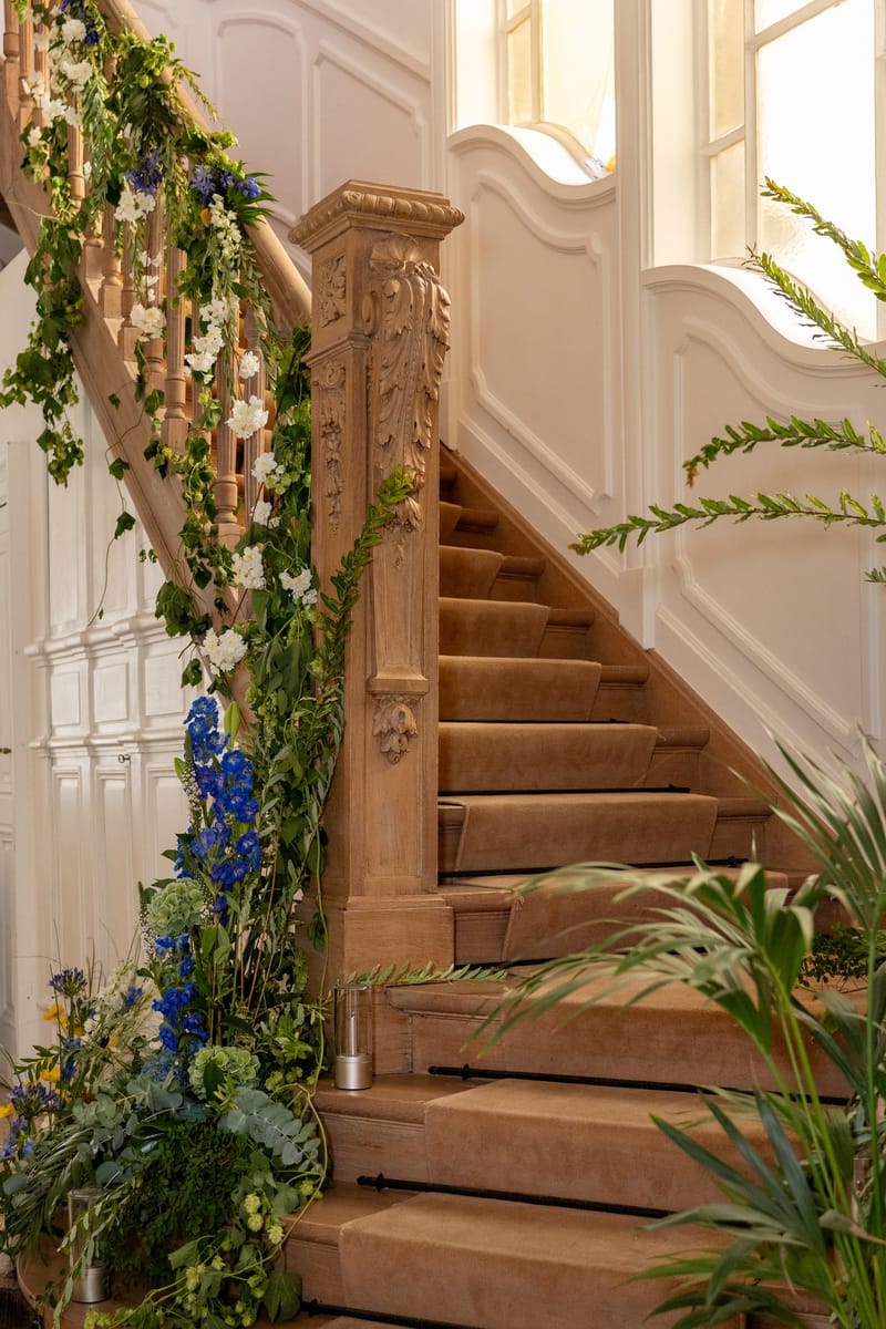 Escalier en bois sculpté orné d'une guirlande de fleurs bleues et blanches