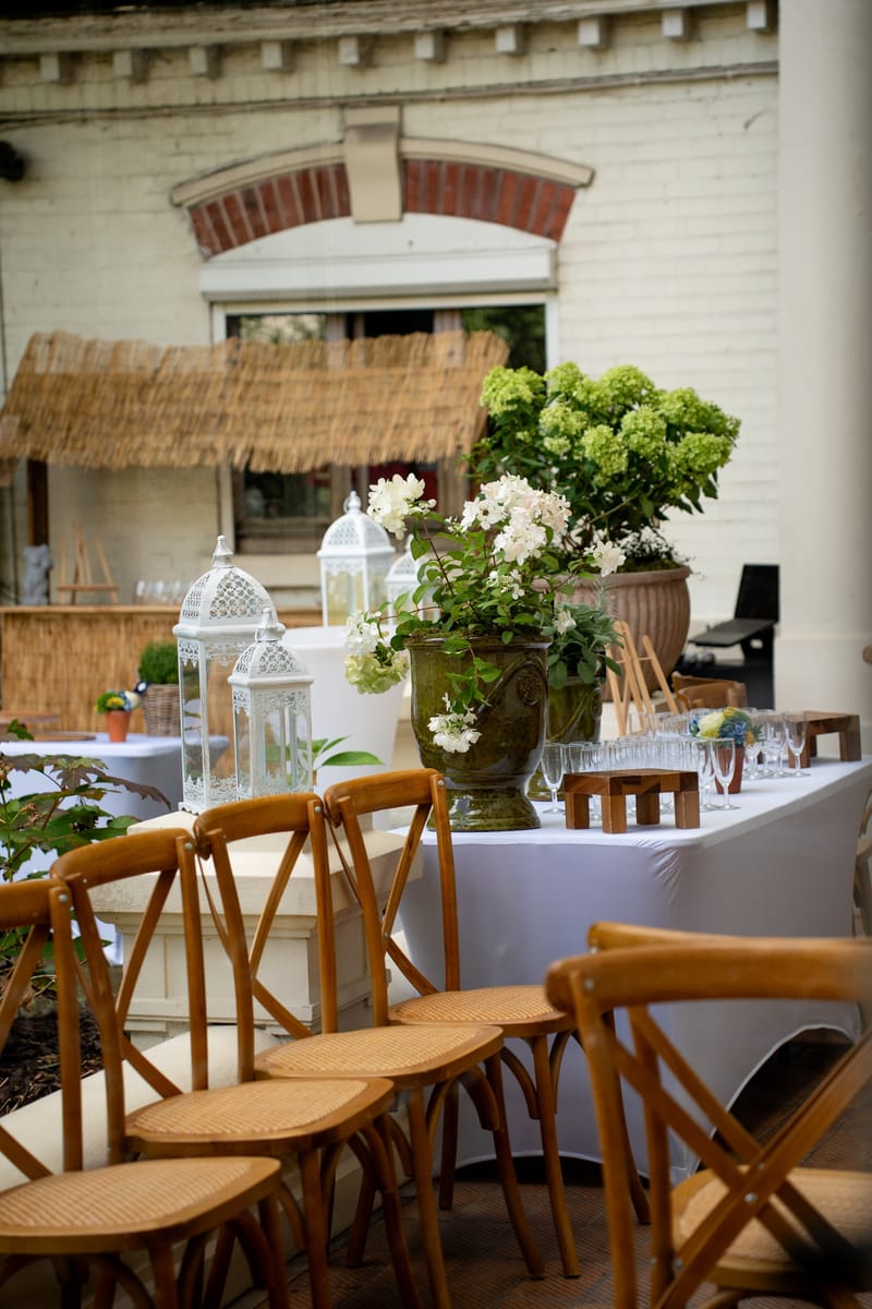 Terrasse avec chaises en bois, lanternes blanches et buffet de boissons