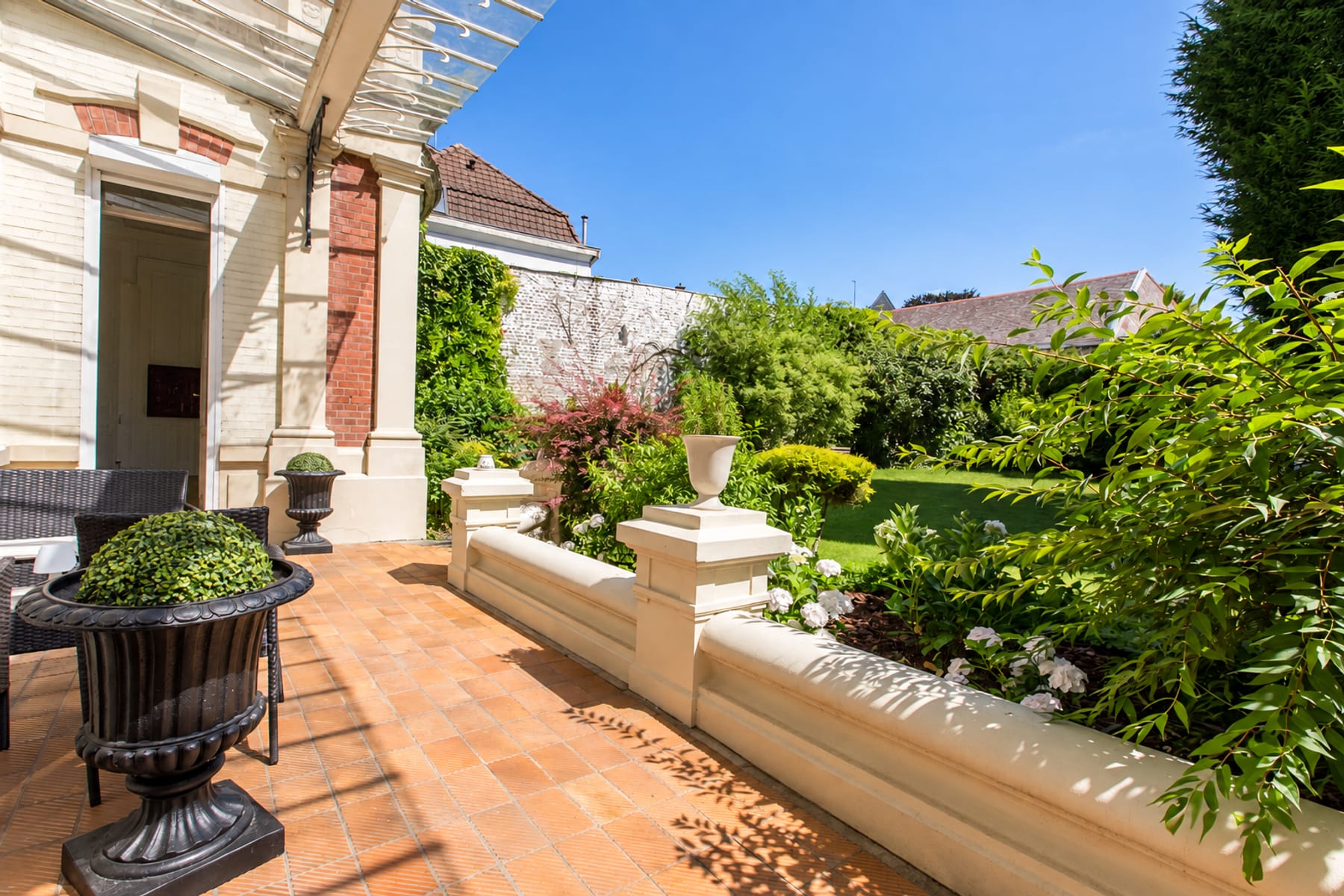 Terrasse et jardin clos du 119, pergola, massifs fleuris et pelouse verdoyante en fond