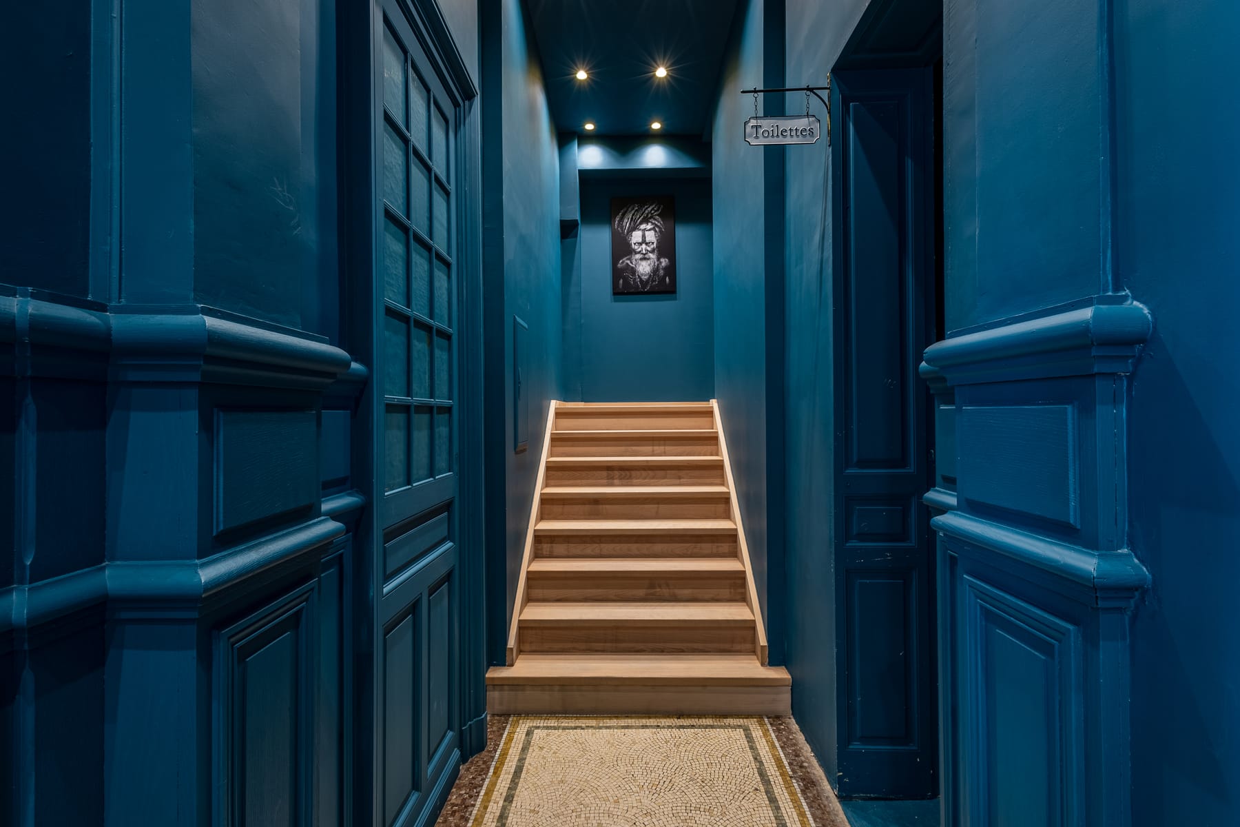 Escalier en bois menant à l'étage du 119, couloir aux murs bleu profond et boiseries anciennes