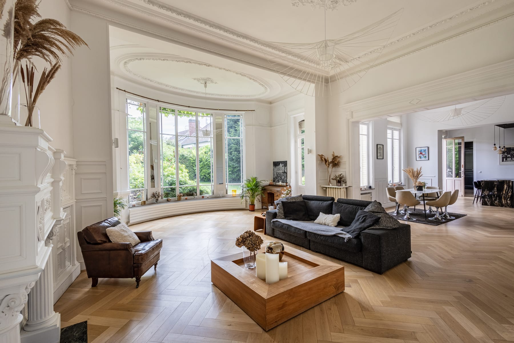 Grand salon en rotonde du 119, moulures, parquet en chevrons et baie vitrée panoramique sur le jardin